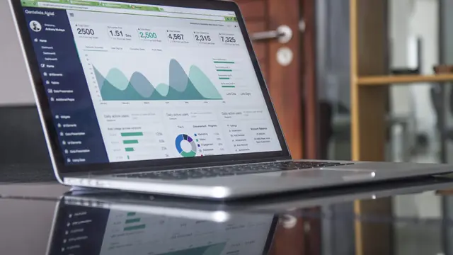 Laptop na biurku z otwartym panelem statystyk i wykresów