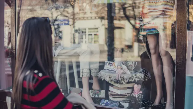 Kobieta oglądająca witrynę sklepu z manekinami i wystawą